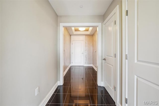 hallway with a tray ceiling and baseboards