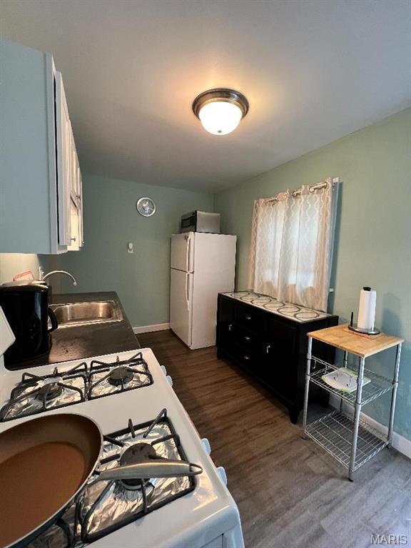 6746 Vernon Ave, University City, MO 63130 - kitchen with a sink, white appliances, baseboards, and dark wood-style flooring