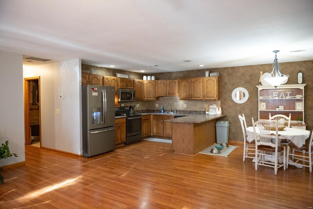 12332 Triple E Ln, Berger, MO 63014 - kitchen featuring stainless steel appliances, a peninsula, a sink, light wood-style flooring, and brown cabinets