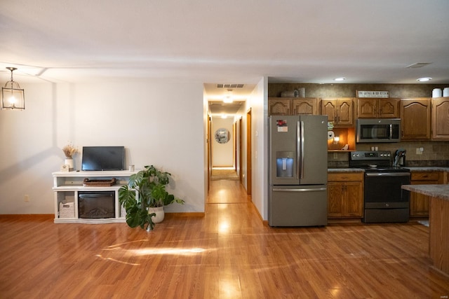 12332 Triple E Ln, Berger, MO 63014 - kitchen with stainless steel appliances, brown cabinetry, wood finished floors, and dark countertops