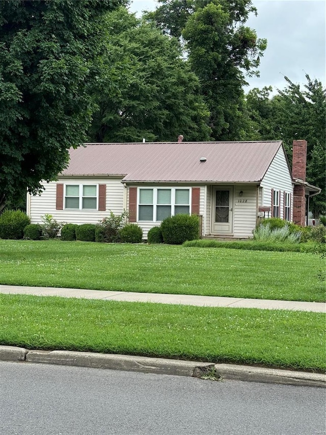 1028 Main St, New Madrid, MO 63869 - ranch-style house featuring a front yard, a chimney, and metal roof