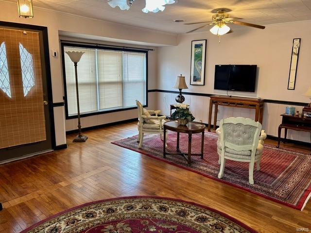 1028 Main St, New Madrid, MO 63869 - living area with wood finished floors, wainscoting, ceiling fan, and ornamental molding
