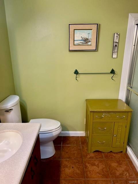 1028 Main St, New Madrid, MO 63869 - bathroom with tile patterned floors, toilet, vanity, baseboards, and a shower with door