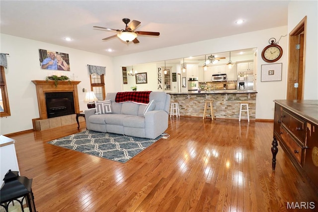 18921 Pleasant View Ln, Lebanon, MO 65536 - living area featuring ceiling fan, wood-type flooring, a tiled fireplace, baseboards, and recessed lighting