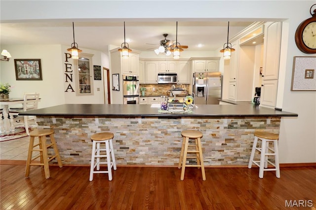 18921 Pleasant View Ln, Lebanon, MO 65536 - kitchen with stainless steel appliances, dark countertops, a peninsula, dark wood-style flooring, and a ceiling fan