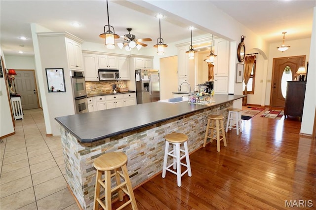 18921 Pleasant View Ln, Lebanon, MO 65536 - kitchen featuring stainless steel appliances, dark countertops, a peninsula, a kitchen bar, and a sink