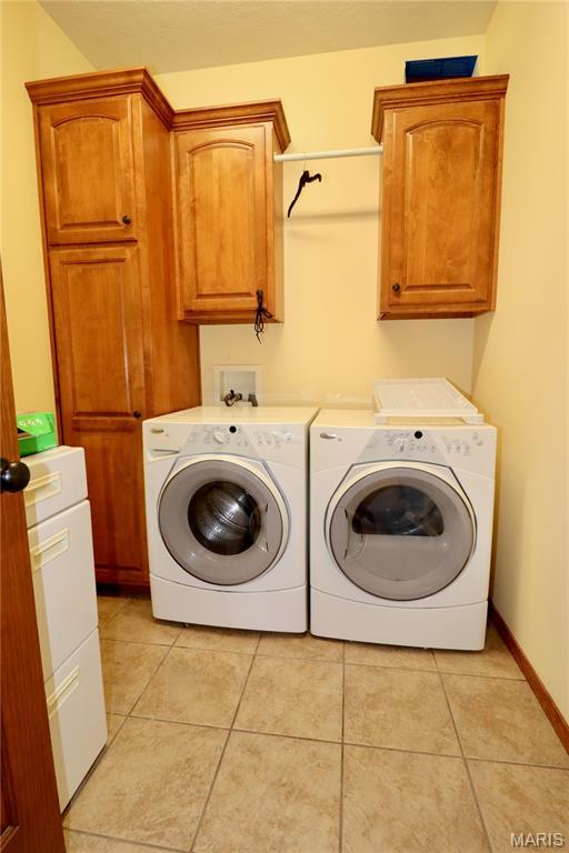 18921 Pleasant View Ln, Lebanon, MO 65536 - washroom with washing machine and clothes dryer, cabinet space, and light tile patterned flooring