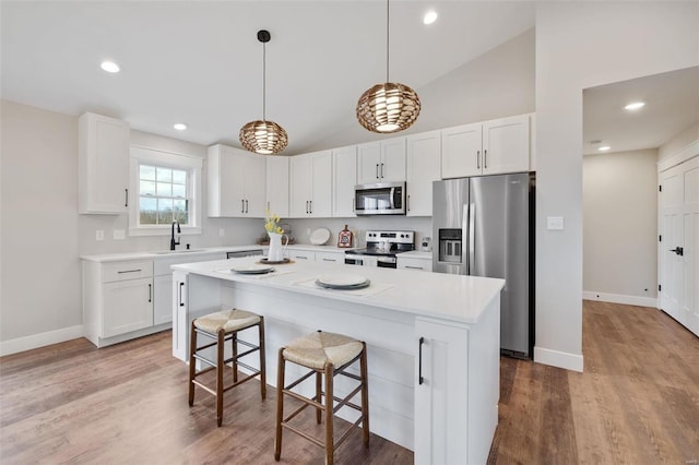 1162 Hawthorne Dr, Desloge, MO 63601 - kitchen featuring appliances with stainless steel finishes, a sink, a breakfast bar area, light countertops, and vaulted ceiling