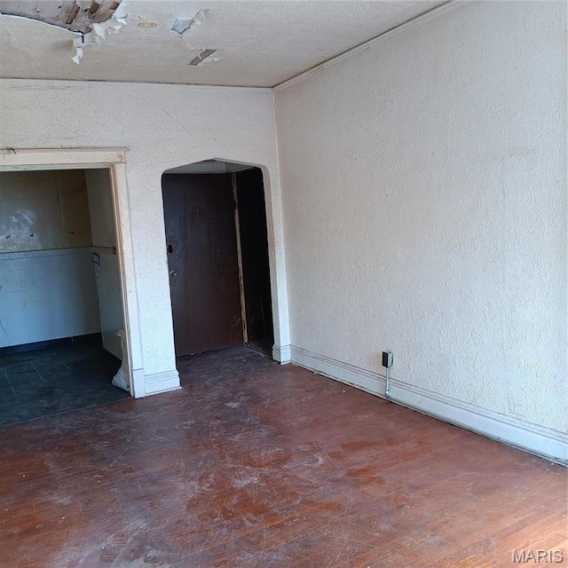 4341 Shreve Ave, Saint Louis, MO 63115 - unfurnished bedroom with arched walkways, baseboards, and a textured wall