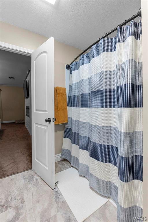 912 Westview Dr, Sikeston, MO 63801 - full bathroom featuring a textured ceiling, baseboards, and curtained shower
