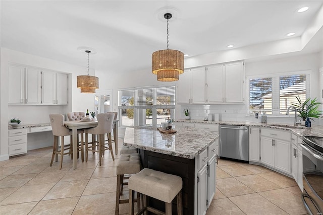 kitchen featuring appliances with stainless steel finishes, a sink, light tile patterned flooring, plenty of natural light, and recessed lighting