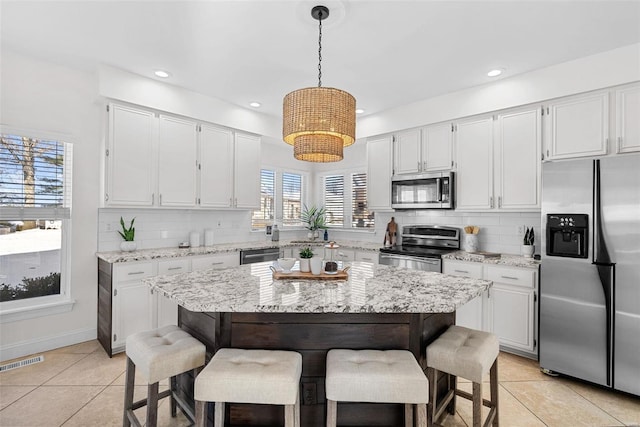 kitchen featuring appliances with stainless steel finishes, light tile patterned floors, a breakfast bar, backsplash, and recessed lighting