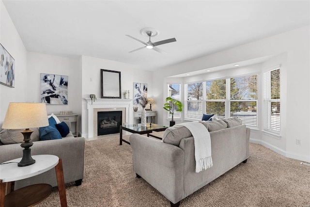 living room featuring carpet flooring, ceiling fan, a fireplace with flush hearth, and baseboards