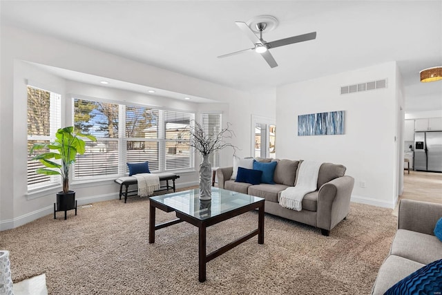 living room featuring baseboards, plenty of natural light, ceiling fan, and light colored carpet