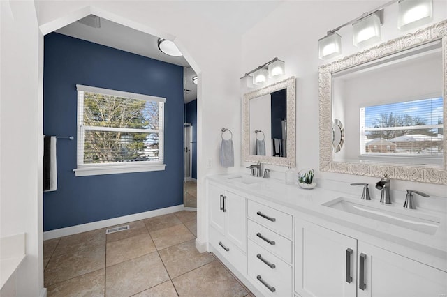 full bath with double vanity, tile patterned flooring, and baseboards