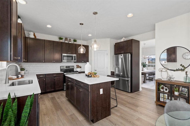 1035 Red Fox Dr, Eureka, MO 63025 - kitchen with stainless steel appliances, a sink, dark brown cabinets, a center island, and light wood finished floors