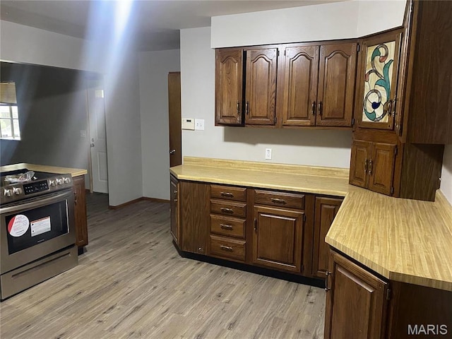 1445 Fairmeadows Ln, Saint Louis, MO 63138 - kitchen with stainless steel electric stove, light countertops, light wood-type flooring, and dark brown cabinetry