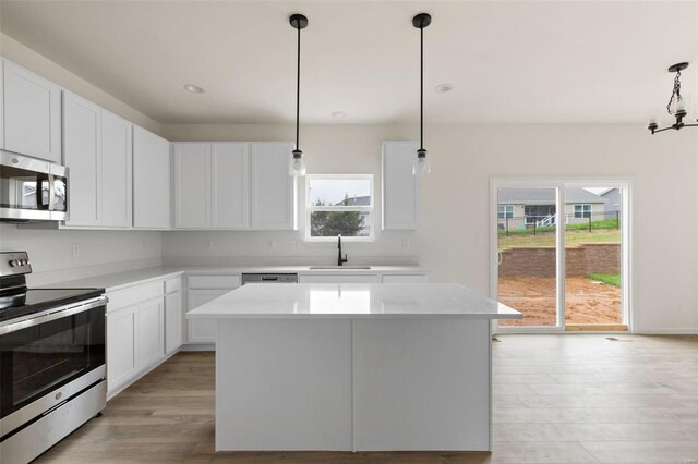 1741 Martingale Ln, Eureka, MO 63025 - kitchen featuring appliances with stainless steel finishes, a sink, light wood finished floors, light countertops, and a center island