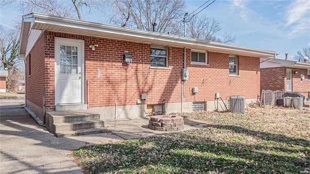 1370 Reale Ave, Saint Louis, MO 63138 - rear view of property with brick siding, an outdoor fire pit, cooling unit, and entry steps