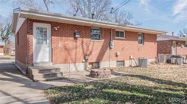 1370 Reale Ave, Saint Louis, MO 63138 - rear view of house with central AC, a fire pit, brick siding, and entry steps