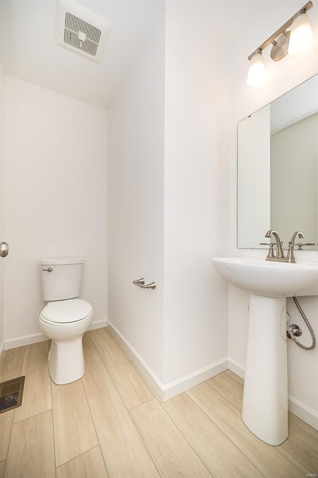 103 Cardow Dr Unit 169-605, Ofallon, MO 63368 - half bathroom featuring wood finished floors, toilet, a sink, and baseboards