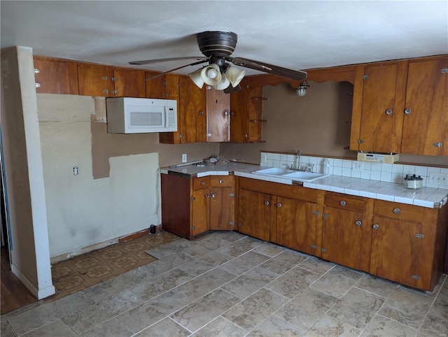 413 N 6th St, New Douglas, IL 62074 - kitchen featuring a sink, white microwave, brown cabinets, ceiling fan, and light countertops