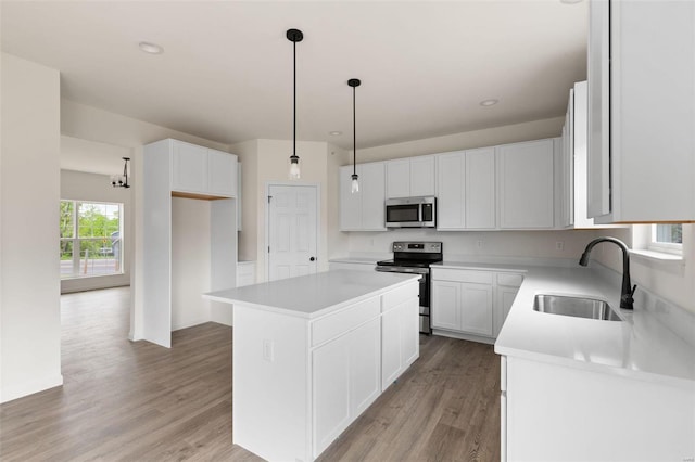 117 Harrow Dr, Ofallon, MO 63385 - kitchen featuring appliances with stainless steel finishes, a sink, a kitchen island, light wood-style floors, and white cabinetry