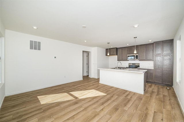 kitchen featuring appliances with stainless steel finishes, a sink, light wood-type flooring, dark brown cabinetry, and recessed lighting