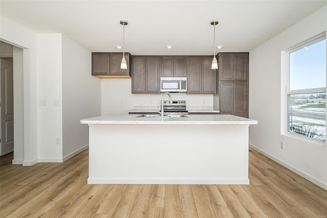 kitchen featuring appliances with stainless steel finishes, a sink, light countertops, and dark brown cabinetry
