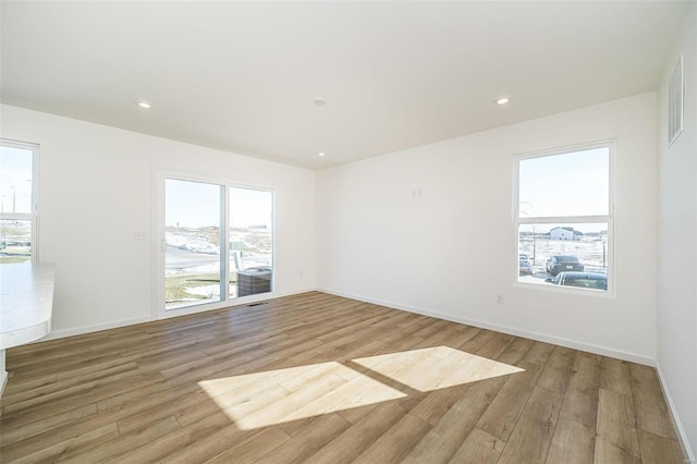 empty room featuring light wood-style floors, plenty of natural light, baseboards, and recessed lighting
