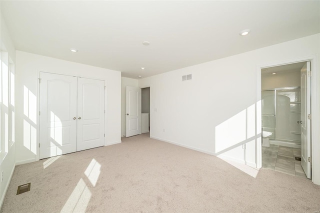 unfurnished bedroom with light colored carpet, a closet, recessed lighting, connected bathroom, and baseboards
