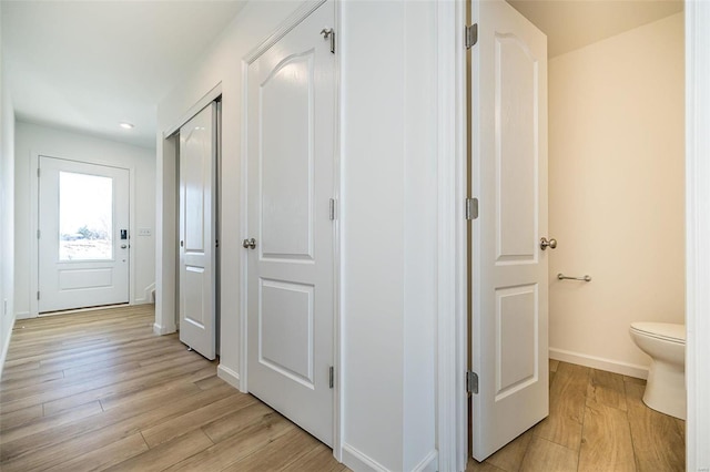 corridor featuring light wood-style flooring, baseboards, and recessed lighting