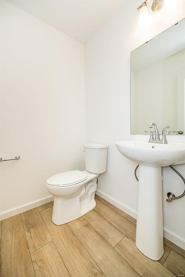 bathroom with toilet, wood finished floors, and baseboards