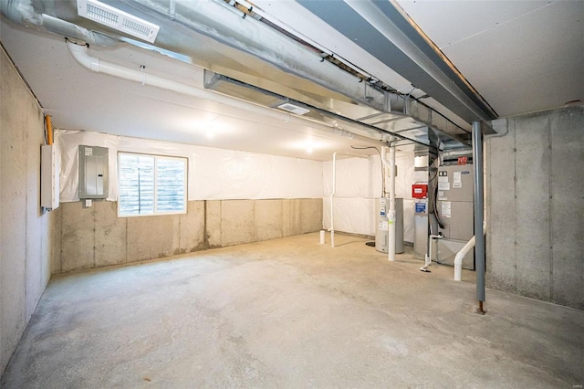 basement with heating unit, electric panel, and electric water heater