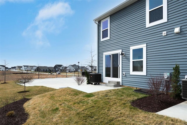 rear view of house with a residential view, a patio area, central air condition unit, and a yard