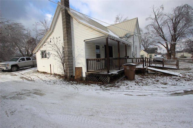 306 S Mine La Motte St, Fredericktown, MO 63645 - view of snow covered exterior featuring a chimney, metal roof, and covered porch
