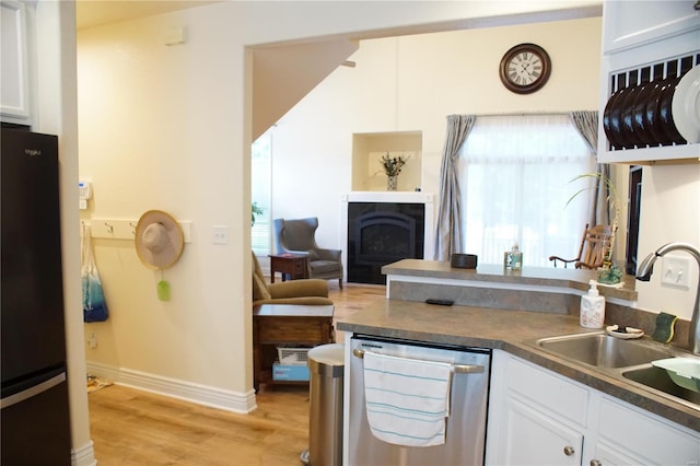 10 Anemone Rd, Lake Ozark, MO 65049 - kitchen with stainless steel dishwasher, freestanding refrigerator, a sink, light wood-style flooring, and white cabinetry