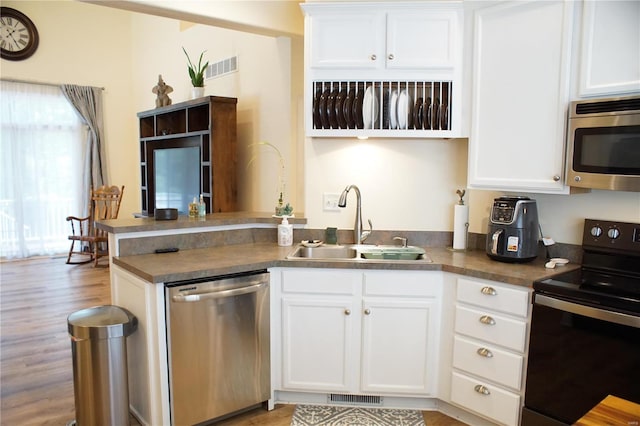10 Anemone Rd, Lake Ozark, MO 65049 - kitchen featuring stainless steel appliances, a sink, a peninsula, white cabinetry, and light wood-style floors
