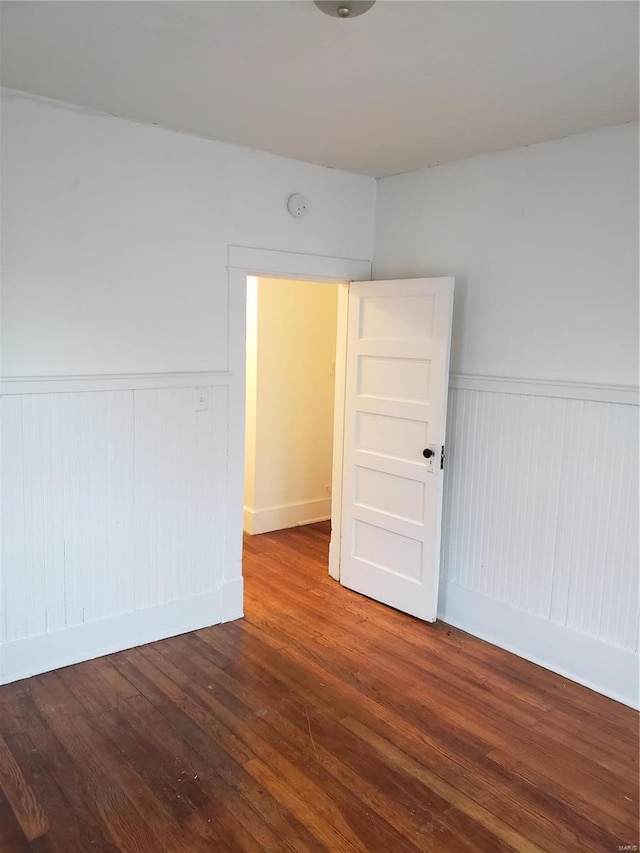 spare room with a wainscoted wall, wood finished floors, and a smoke detector
