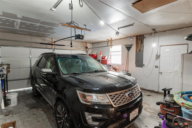 garage with electric panel, a garage door opener, and freestanding refrigerator