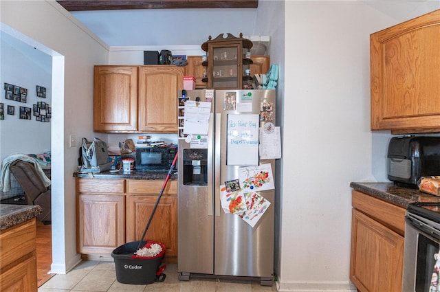 kitchen with appliances with stainless steel finishes, dark countertops, light tile patterned floors, and baseboards