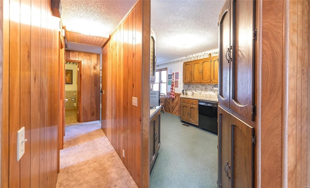 hallway featuring wood walls, a textured ceiling, and light colored carpet
