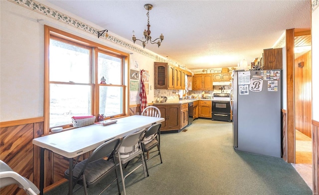 kitchen with freestanding refrigerator, electric range, dishwasher, brown cabinetry, and a chandelier