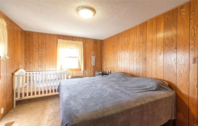 bedroom with carpet, a textured ceiling, and wooden walls