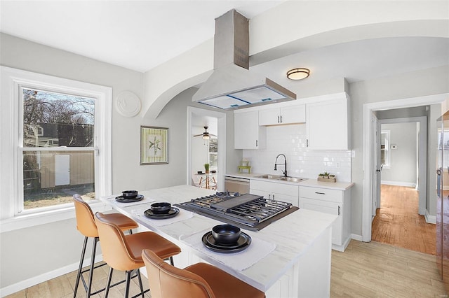 1100 Northdale Ave, Saint Louis, MO 63138 - kitchen featuring a sink, island range hood, white cabinetry, stainless steel gas cooktop, and arched walkways