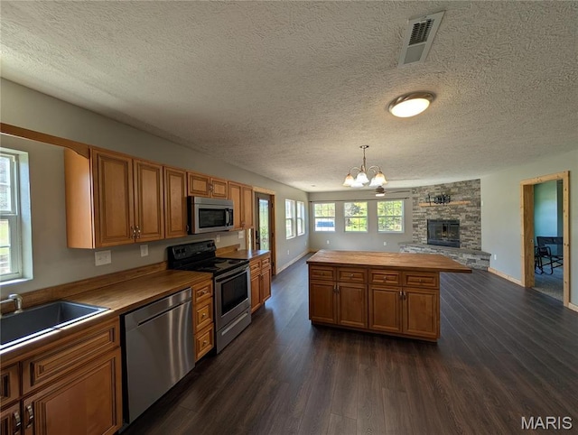 kitchen with stainless steel appliances, wooden counters, a chandelier, dark wood-style flooring, and open floor plan