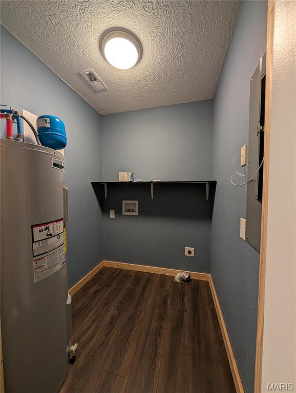 clothes washing area with water heater, hookup for a washing machine, wood finished floors, a textured ceiling, and electric dryer hookup