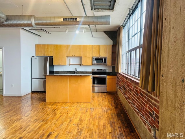 2020 Washington Ave Unit 504, Saint Louis, MO 63103 - kitchen with stainless steel appliances, hardwood / wood-style flooring, a towering ceiling, dark countertops, and a center island with sink