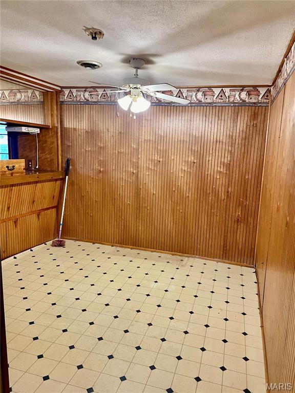 115 Cook Ave, Chaffee, MO 63740 - spare room featuring tile patterned floors, wood walls, a ceiling fan, and a textured ceiling