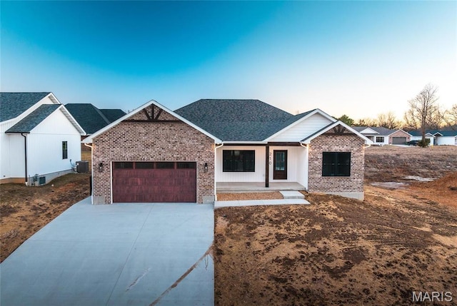 210 Sunny Dr, Rolla, MO 65401 - view of front of property featuring brick siding, a garage, driveway, central AC, and covered porch